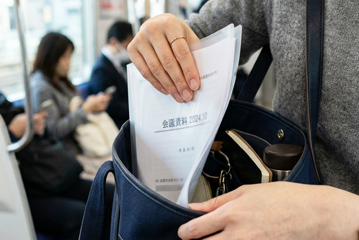 書類が入ったクリアファイルをバッグから取り出している様子